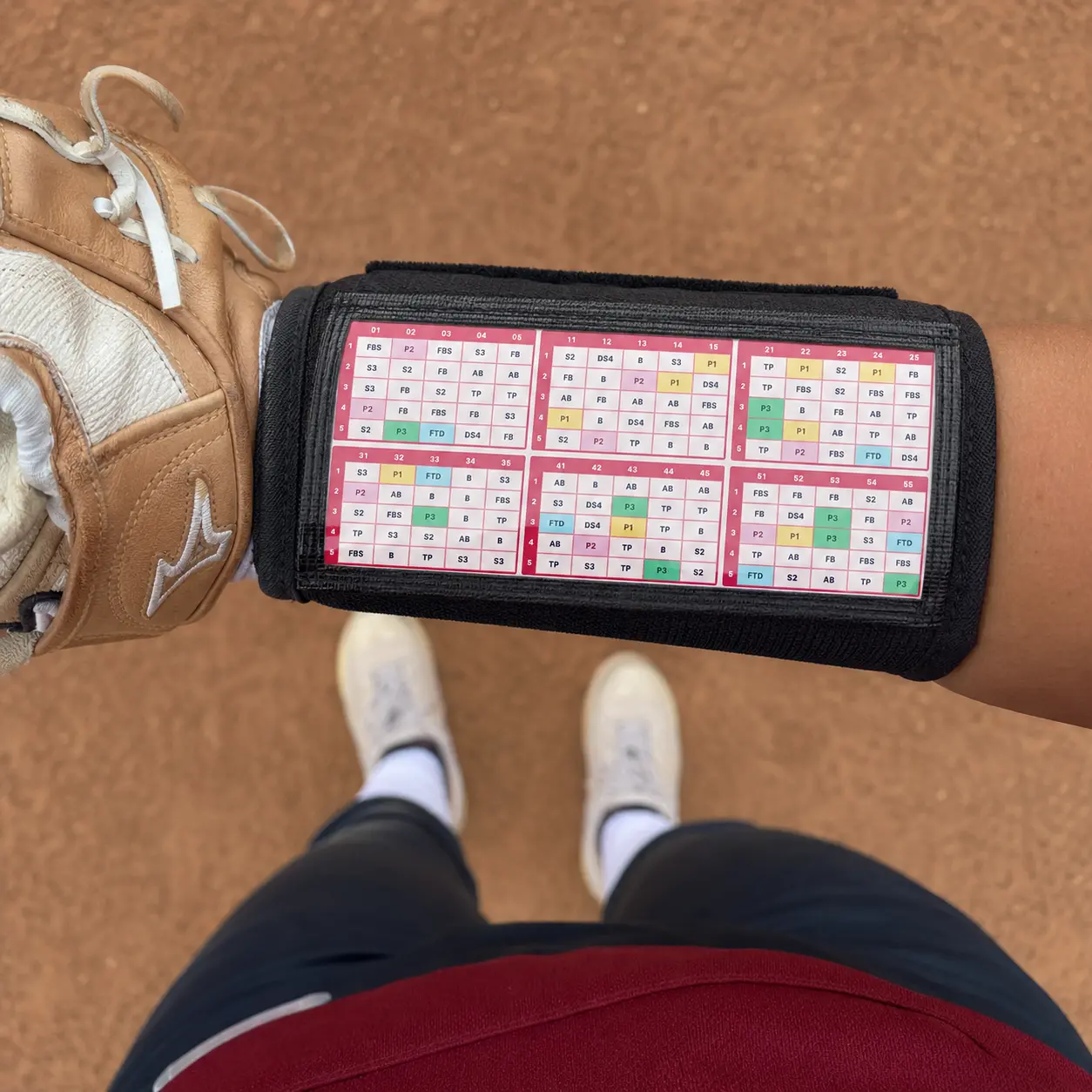 Softball player wearing a printed number-coded wristband on her sleeve, ready to read play calls from the dugout